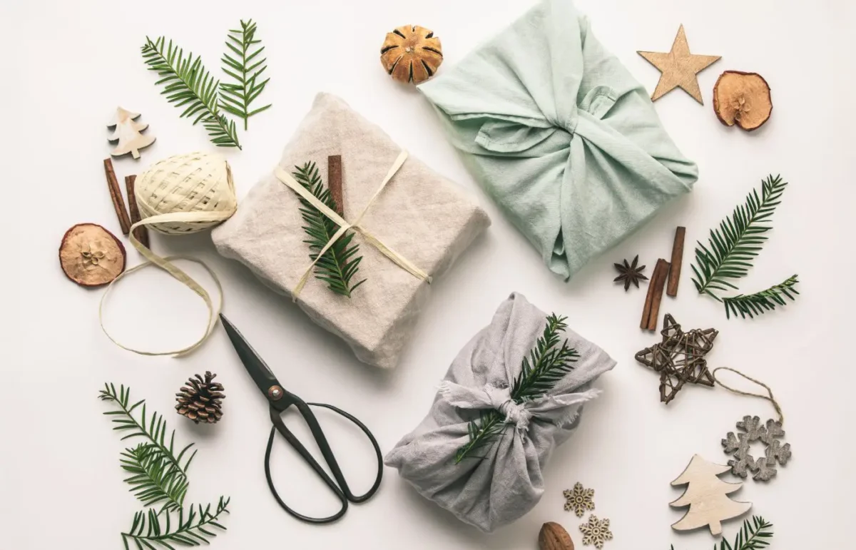 Décorations de Noël écoresponsables : emballages cadeaux en tissu, ornements naturels en bois, branches de sapin et éléments recyclés pour un Noël durable.